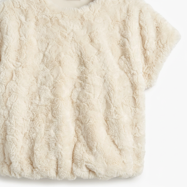 Close-up of the cream faux fur top showing its plush pebble-textured fabric.