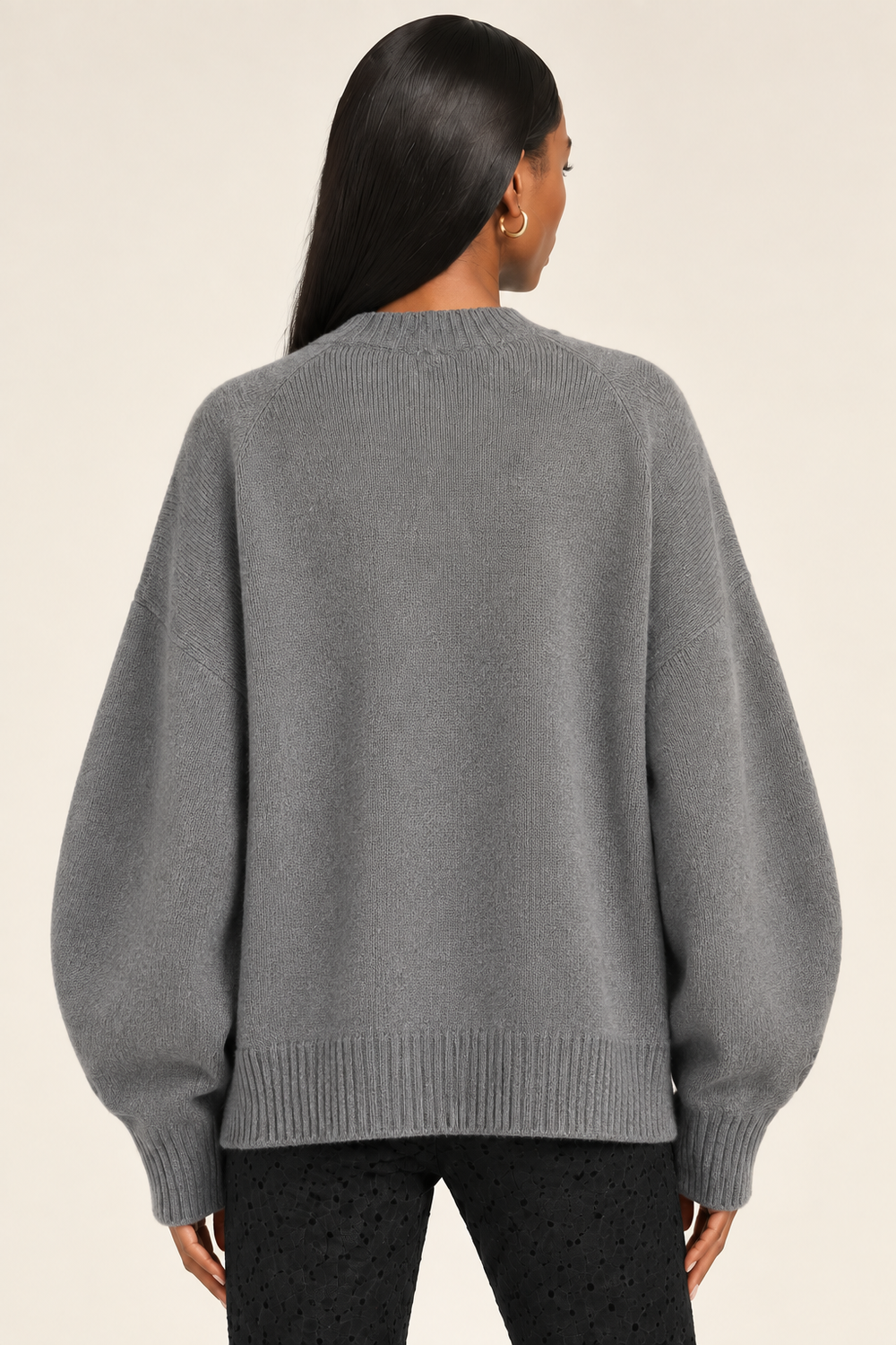 Back hip-up view of Cici wearing gray New York sweater with roomy sleeves