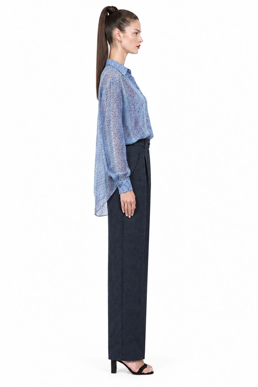 Sloane wearing navy pleated plaid straight-leg trousers with blue printed blouse, side view