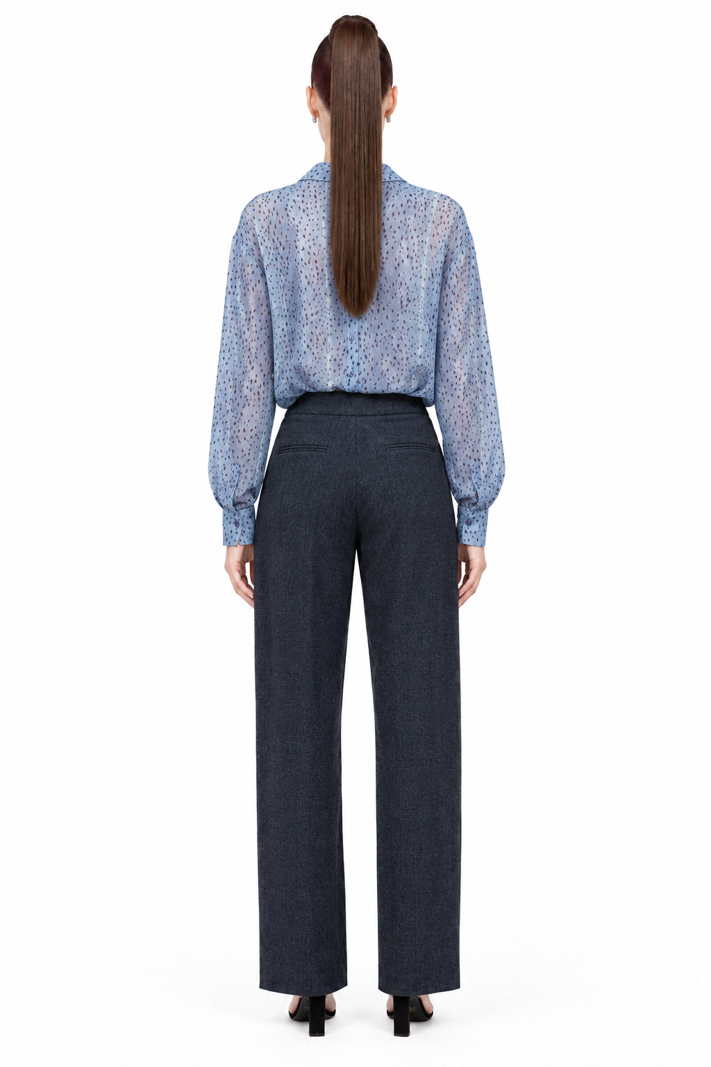 Sloane wearing navy pleated plaid straight-leg trousers with blue printed blouse, back view