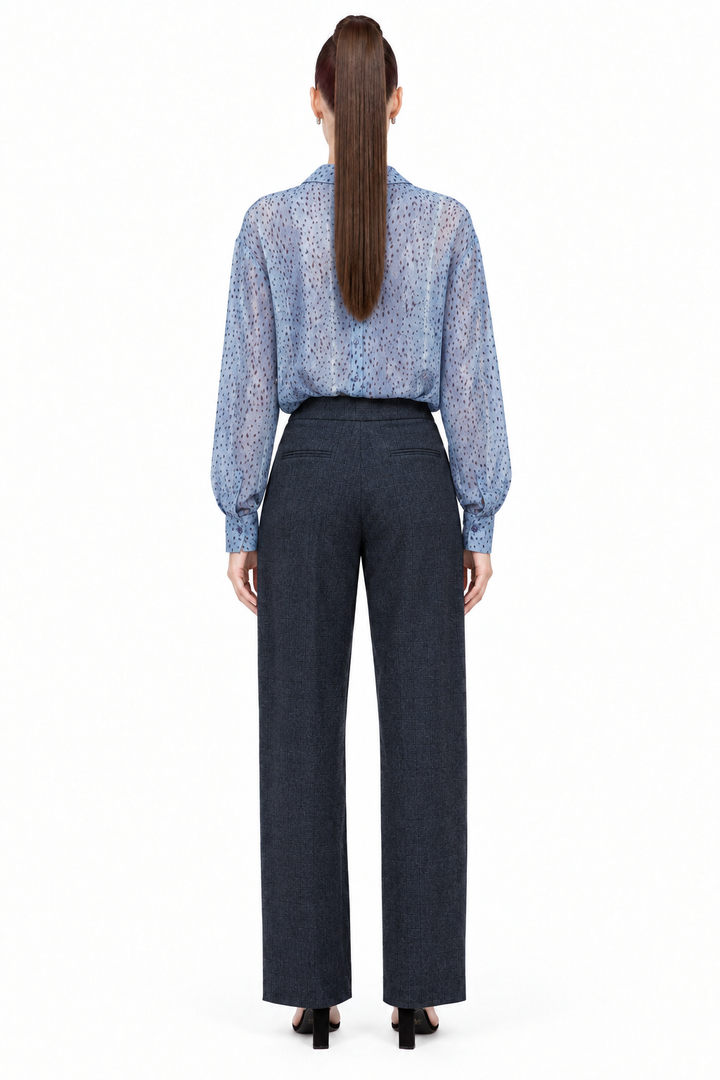 Sloane wearing navy pleated plaid straight-leg trousers with blue printed blouse, back view