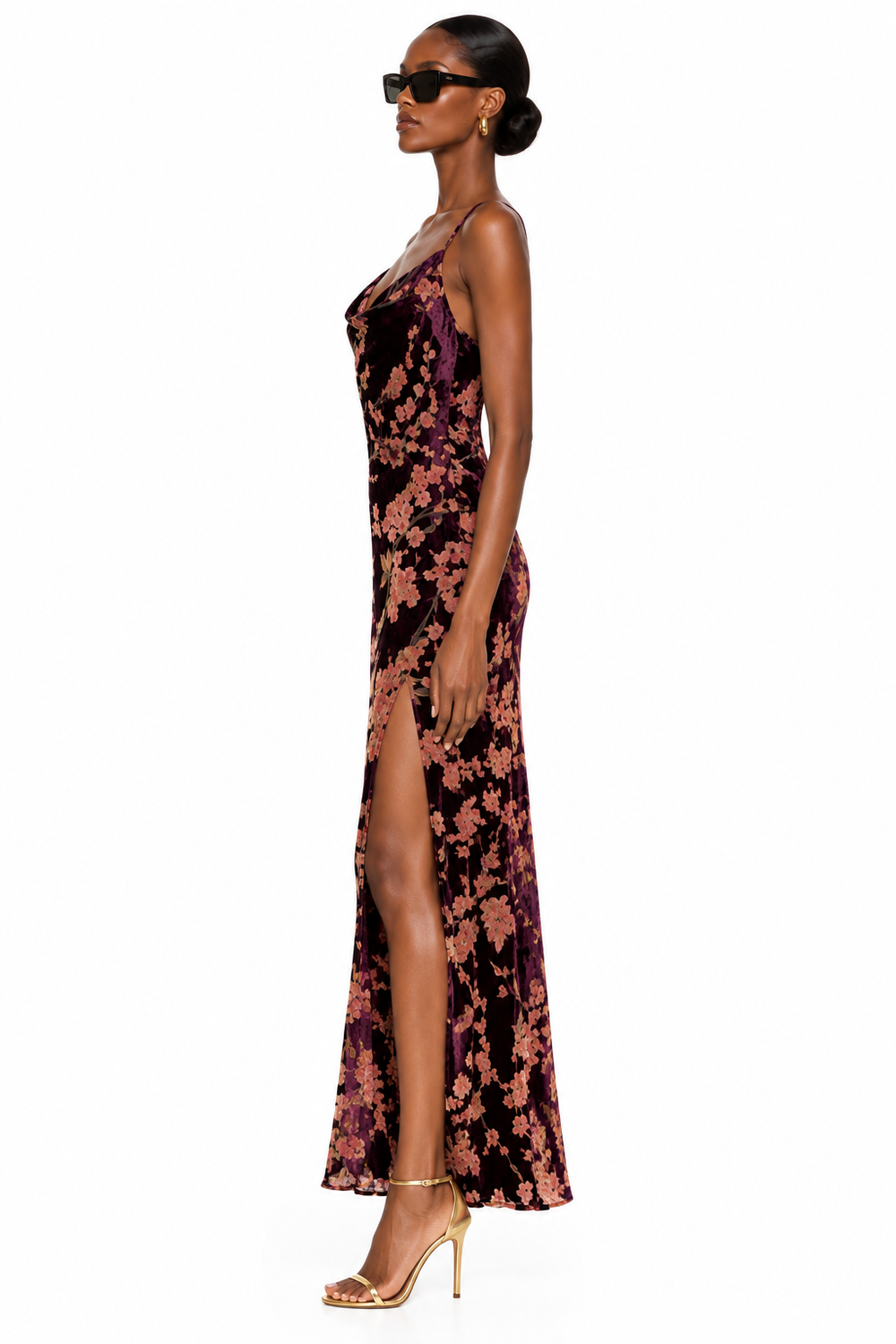 Side view of burgundy floral velvet maxi dress showing side slit and gold heels