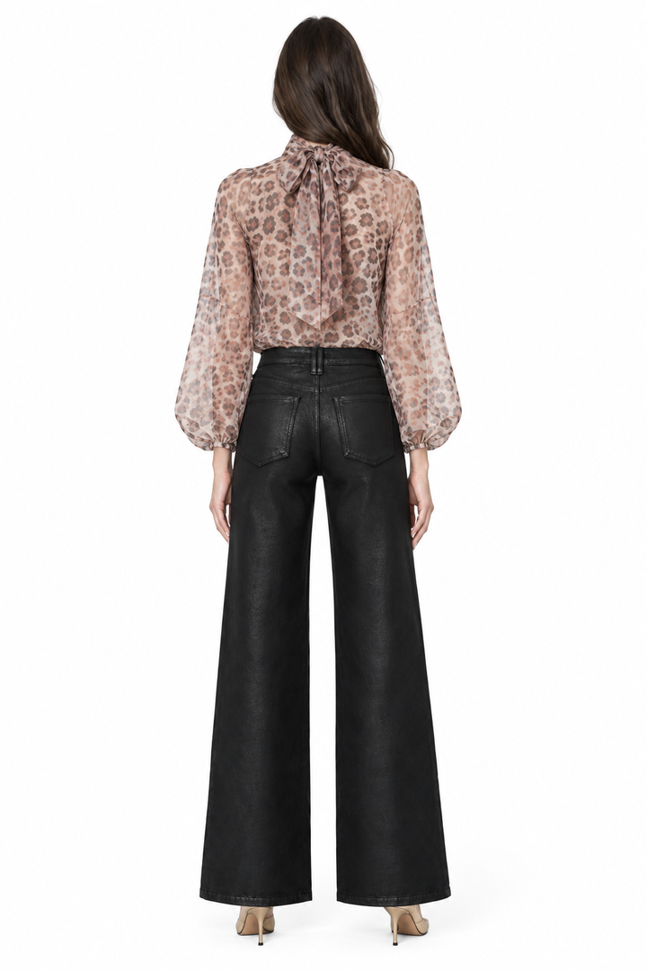Sloane wearing black coated wide-leg jeans with back patch pockets, printed blouse and gold pumps, back view