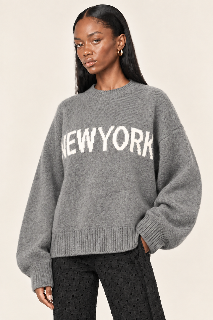 Cici angled hip-up view of gray New York sweater showing relaxed fit and ribbed hem