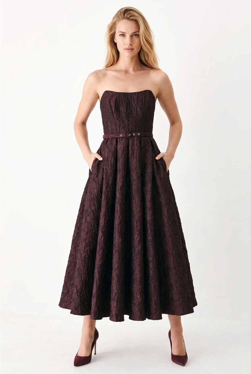 Tricia modeling the burgundy embossed strapless midi dress, front view showing side pockets and wine-colored heels