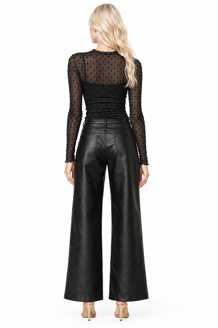 Back view of Tiffany wearing black vegan-leather wide-leg pants showing back pockets with sheer polka-dot top