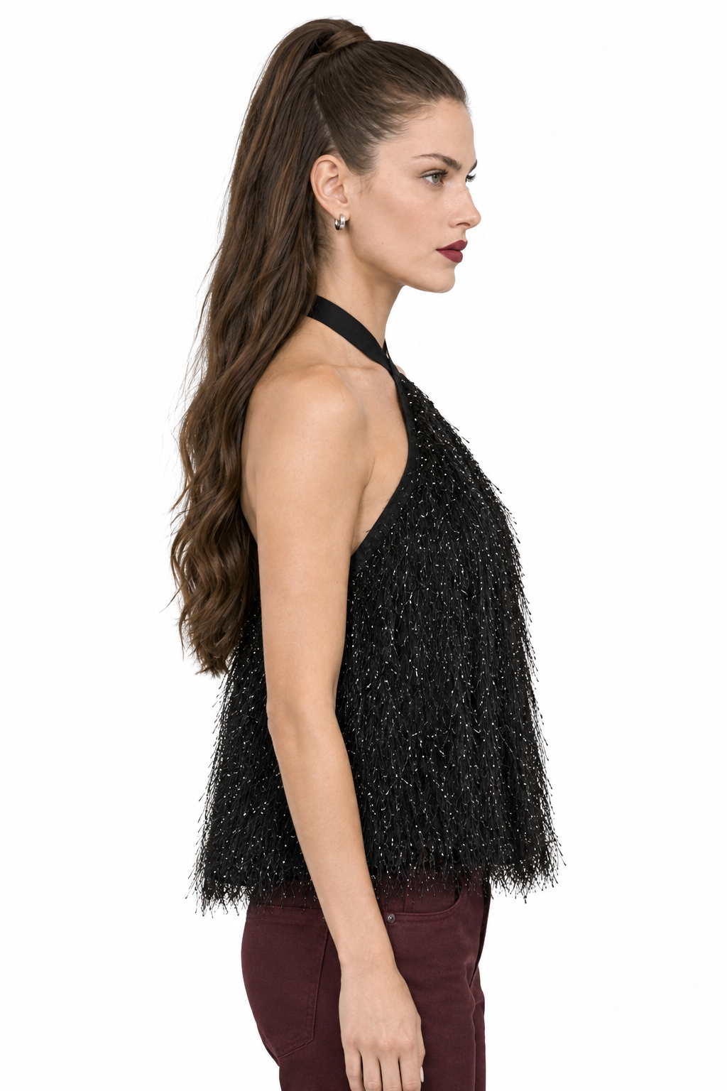 Side view of Sloane wearing black crisscross halter feather-like fringe top with wine pants