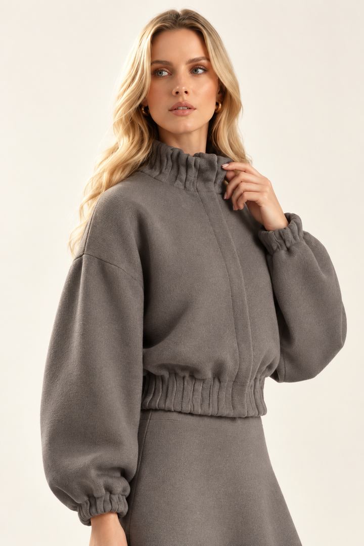 Angled view of Maggie in plain Dark Stone knit jacket showing high collar and balloon sleeve