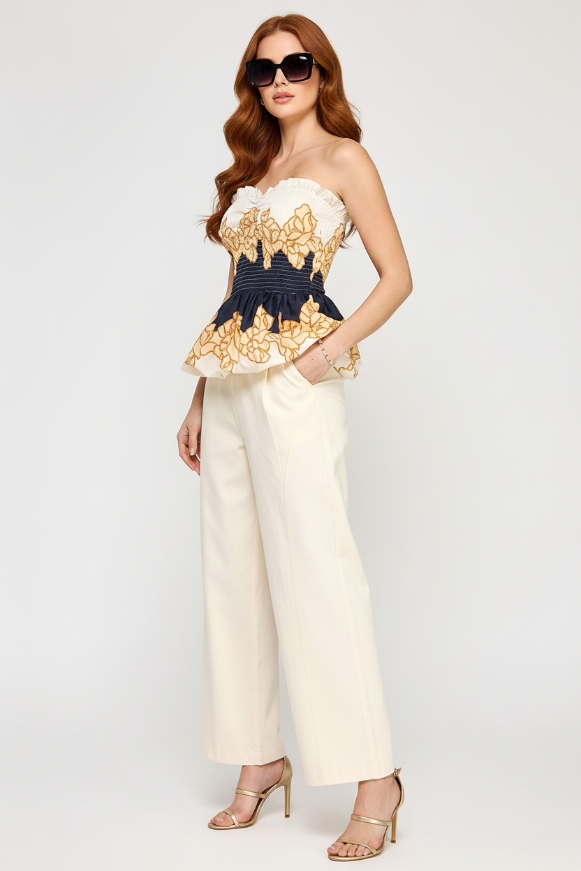 Beciga red hair model wearing navy and cream floral smocked peplum top, three-quarter angle
