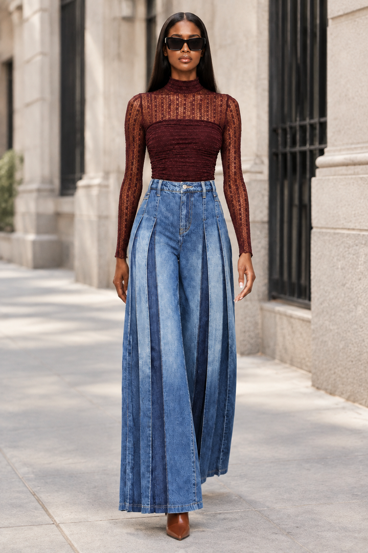 Model walking in dark-wash pleated wide-leg jeans and burgundy bodysuit with cognac heels