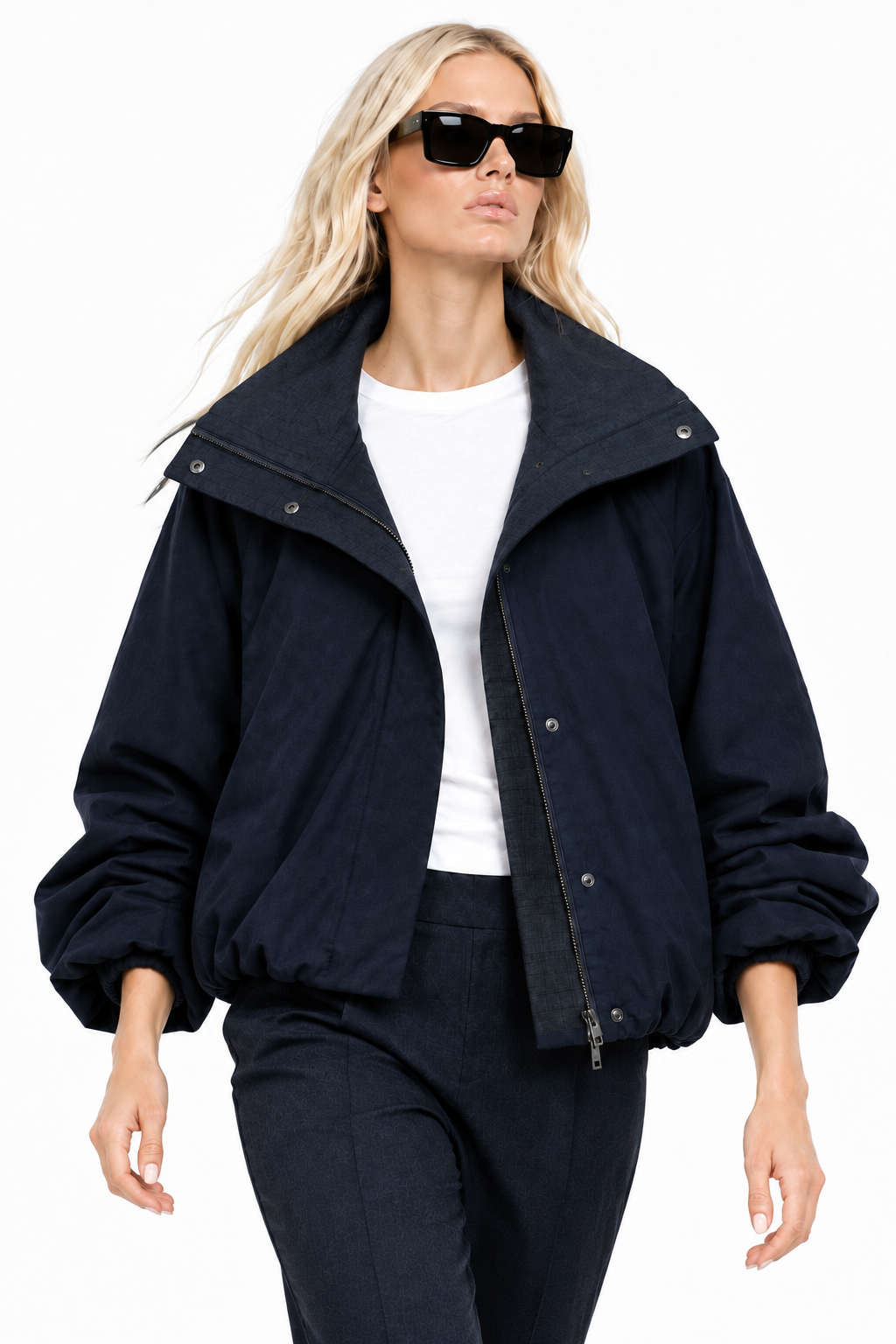 Blonde model walking in navy funnel-neck bomber jacket, lifestyle view