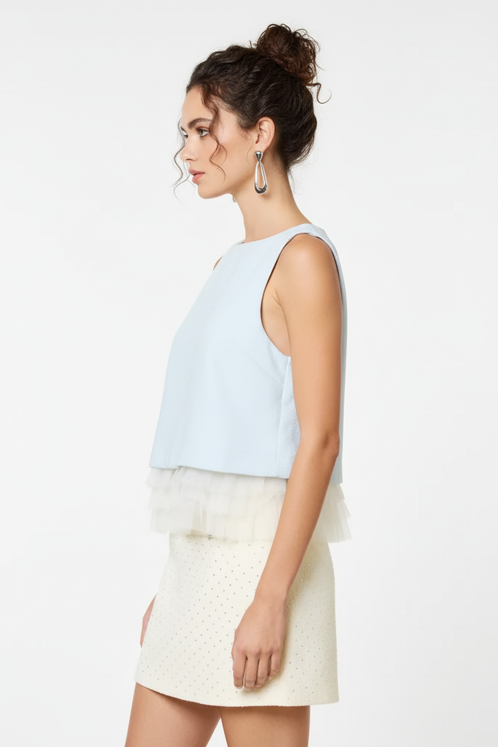 Baby blue sleeveless ruffle hem top - side profile with dark curly messy bun model on white background