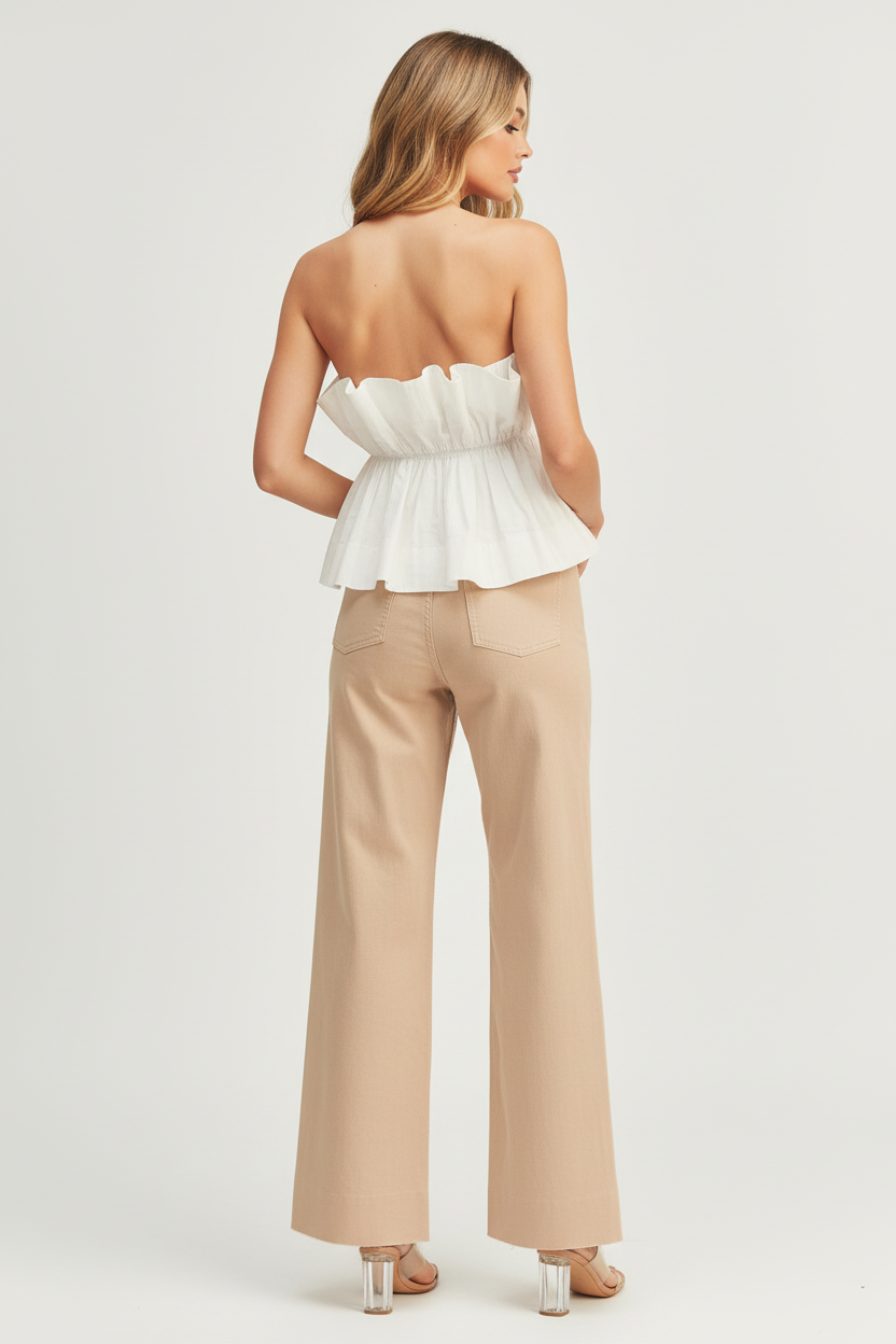Beciga blonde model wearing white peplum tube top with sandy taupe trousers, back view showing ruffle detail