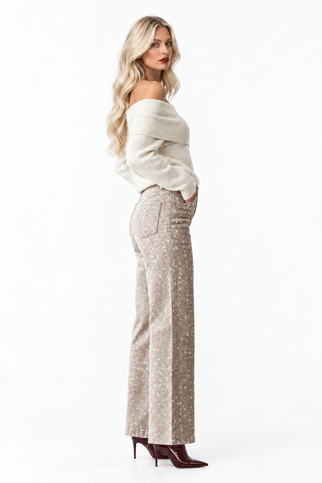 Model in cream off-shoulder sweater and patterned wide-leg pants with dark wine crocodile-embossed boots, side view