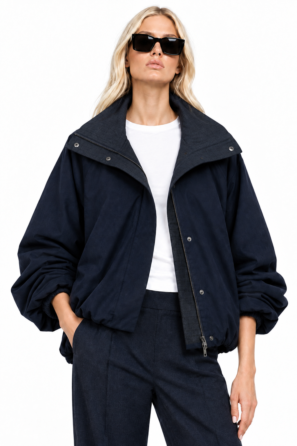 Blonde model wearing navy funnel-neck bomber jacket with open collar, front view