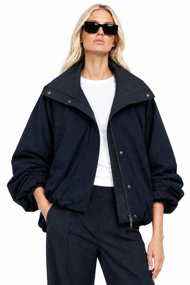 Blonde model wearing navy funnel-neck bomber jacket with open collar, front view