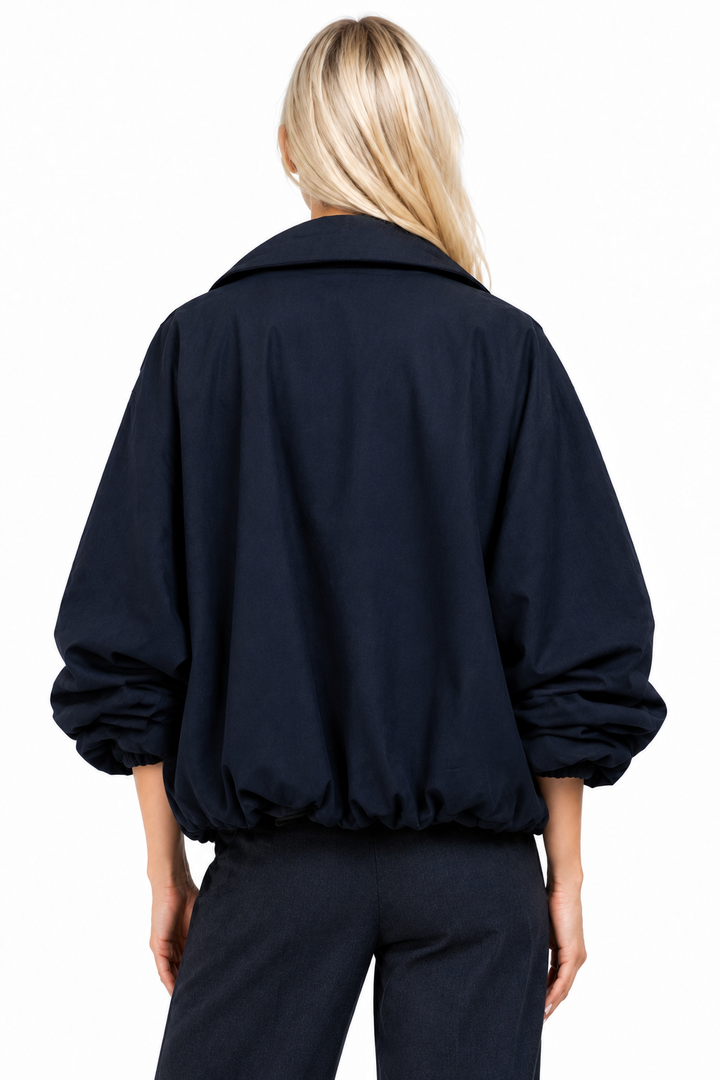Blonde model wearing navy funnel-neck bomber jacket, back view