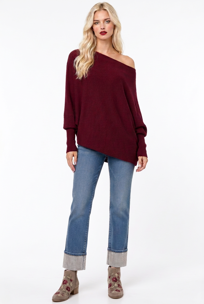 Tiffany wearing the burgundy Amar asymmetric off shoulder sweater with rhinestone cuff jeans and wine-embroidered booties, relaxed front view